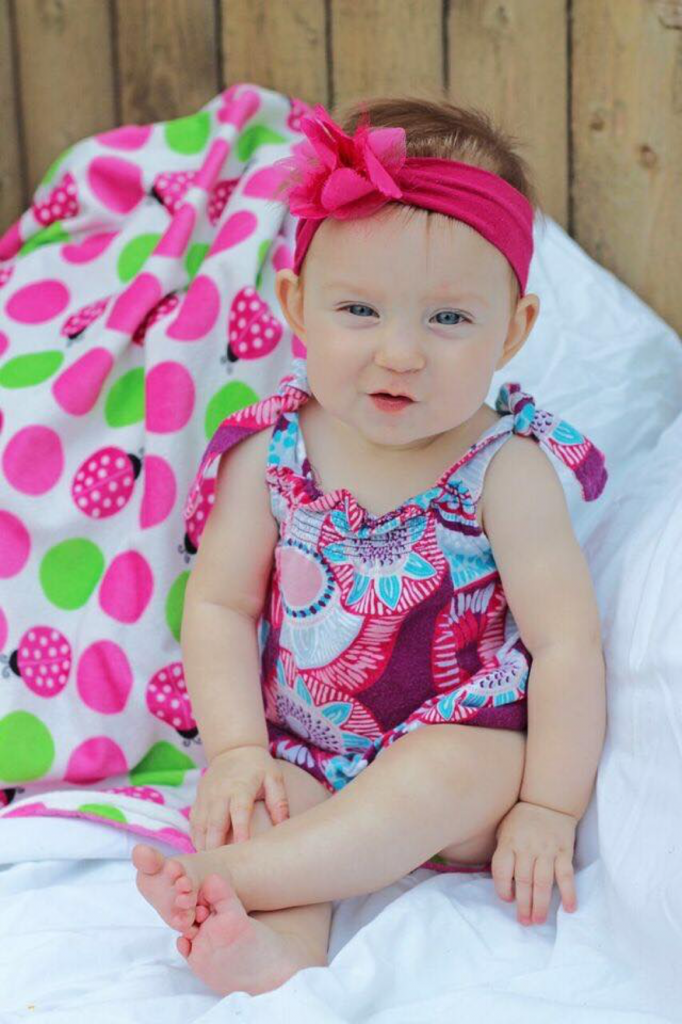 Baby Save Lincoln wears a bright pink dress and pink headband